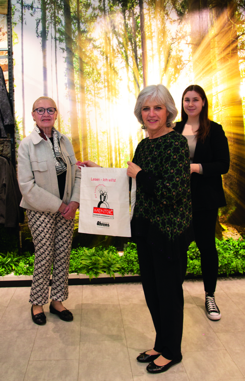 Frau Karin Ahrens bei der Übergabe der Mentoren - Taschen an die Vorsitzende Inge Maisch. Im Hintergrund Giullietta-Katinka Allegretta - Filialleiterin Thalia Marburg (im Kaufhaus Ahrens)